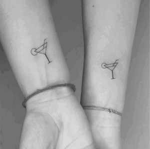 Couple's matching minimalist cocktail tattoos on inner forearms, symbolizing shared experiences and love.